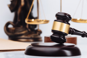A judge’s gavel resting on a sound block, with scales of justice in the background.